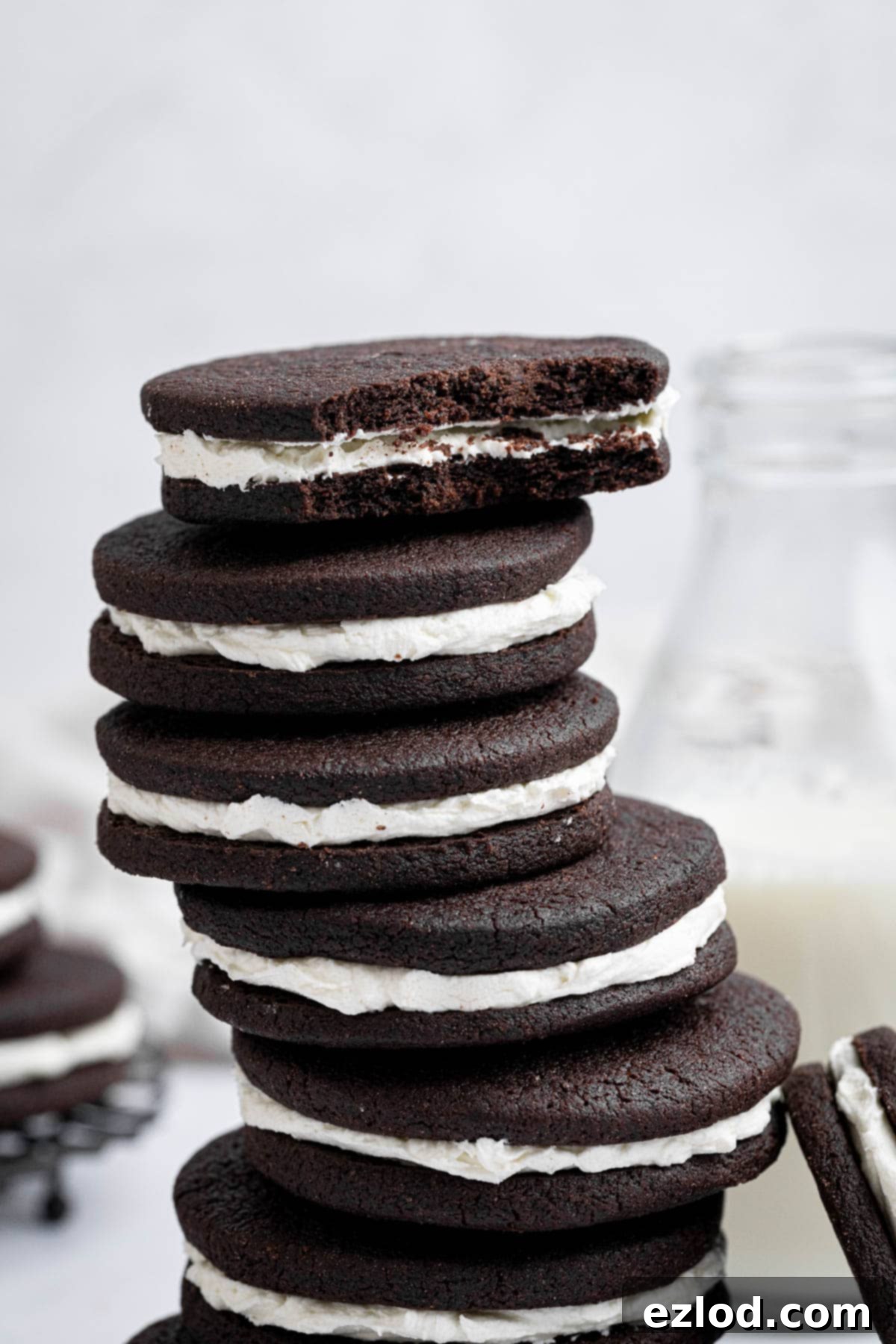 A close-up view of a stack of mint chocolate sandwich cookies, with the top cookie having a bite taken out of it, revealing the layers.