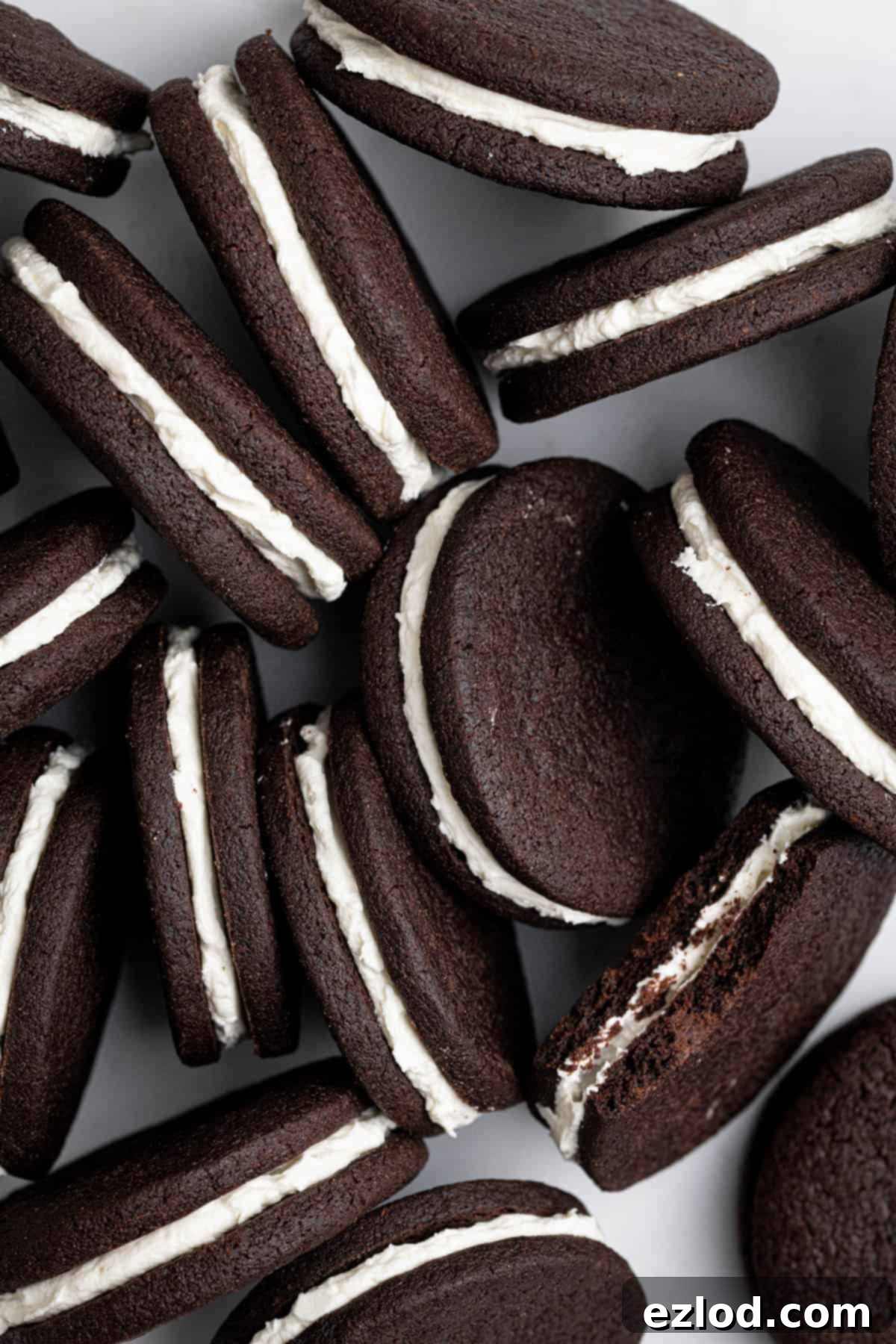 Close-up view of three mint chocolate sandwich cookies, perfectly turned on their sides to showcase the crisp chocolate shortbread and fluffy peppermint buttercream filling.
