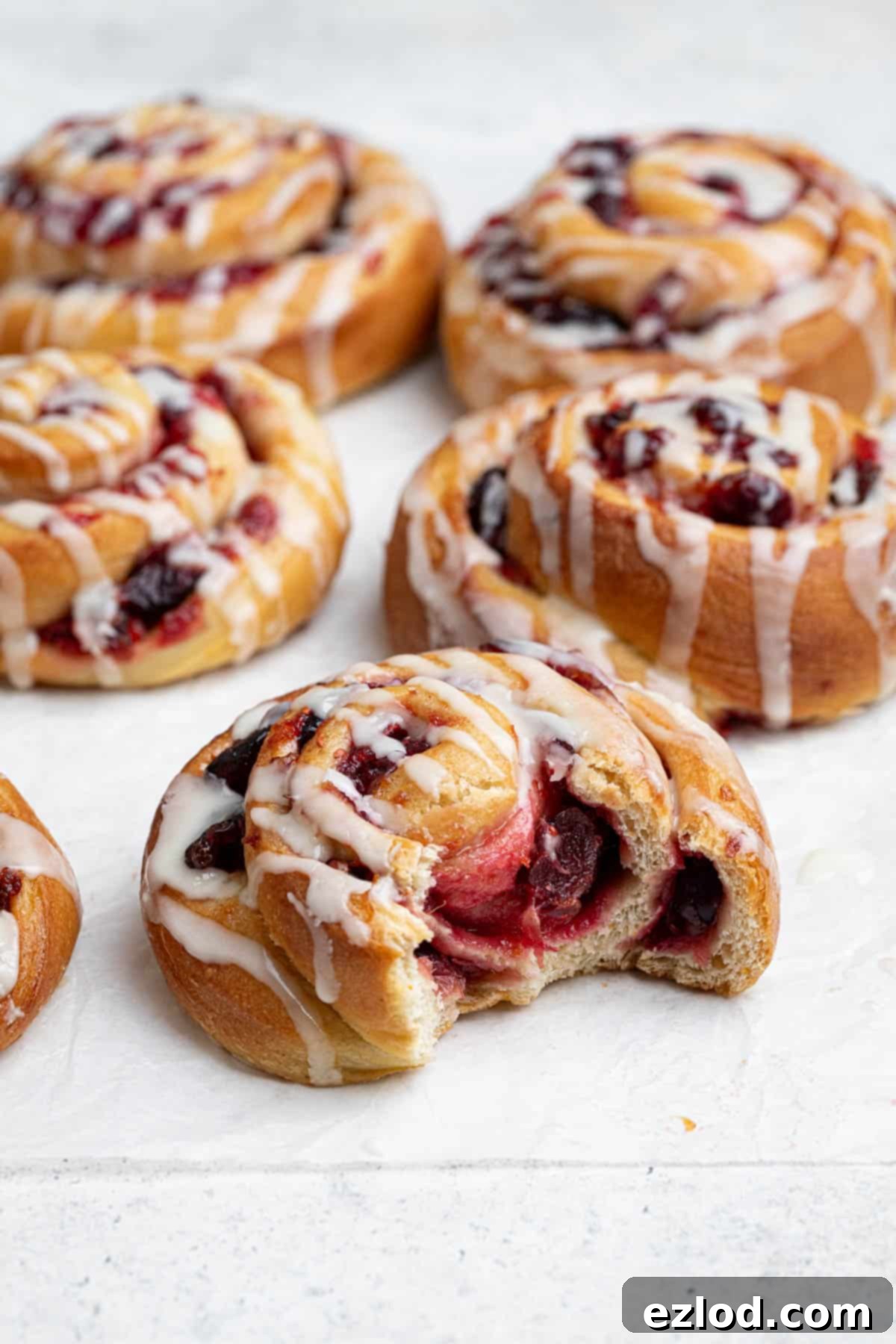 Close up of a vegan cranberry orange roll with a bite taken out of it.