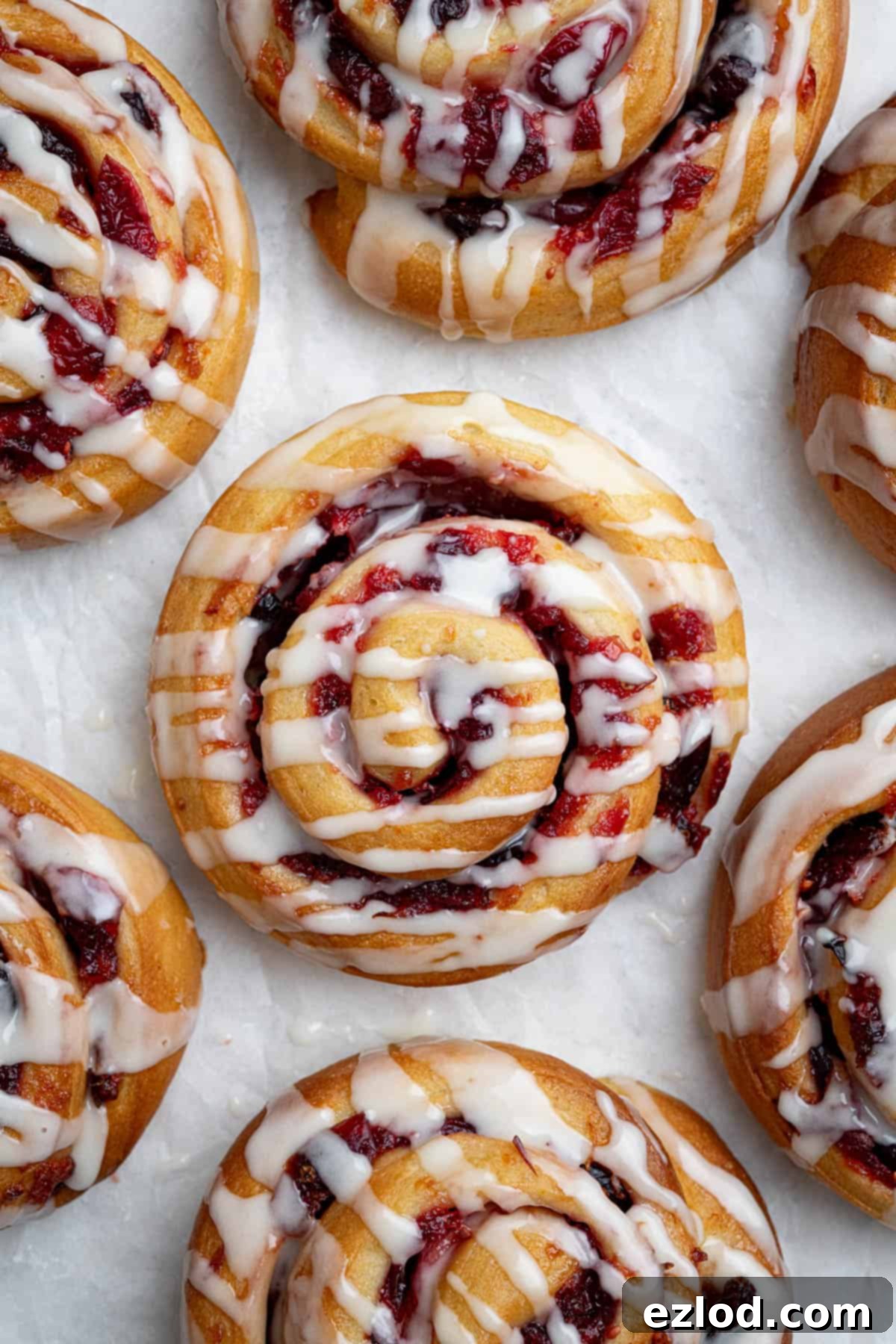 Close up of vegan cranberry orange rolls on a white surface.