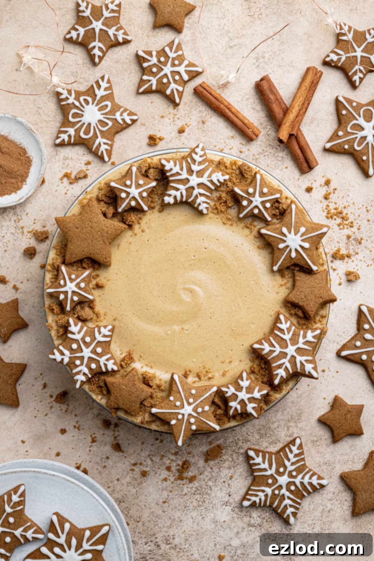 Vegan gingerbread cheesecake surrounded by gingerbread cookies and cinnamon sticks.