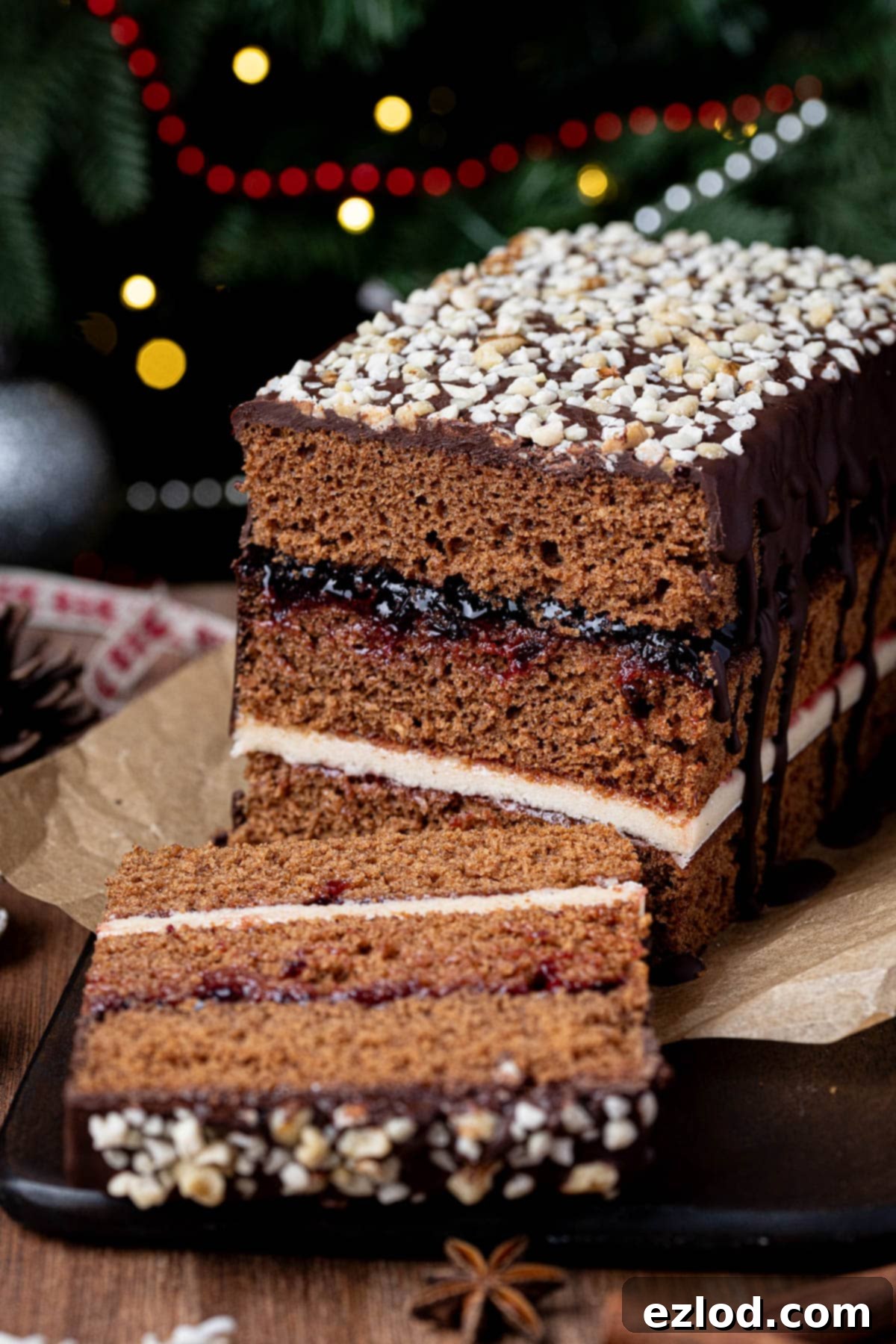 A close-up view of a perfectly sliced piece of Vegan Piernik, revealing the distinct layers of cake, jam, and marzipan, all topped with a rich chocolate glaze.