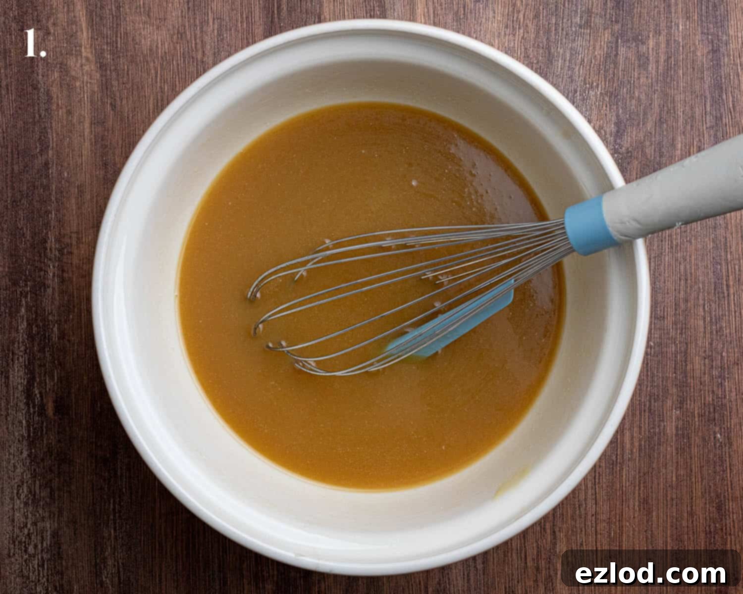 Close-up shot of the wet ingredients for Vegan Piernik, golden syrup, brown sugar, milk, vinegar, and melted butter, whisked together in a large bowl.