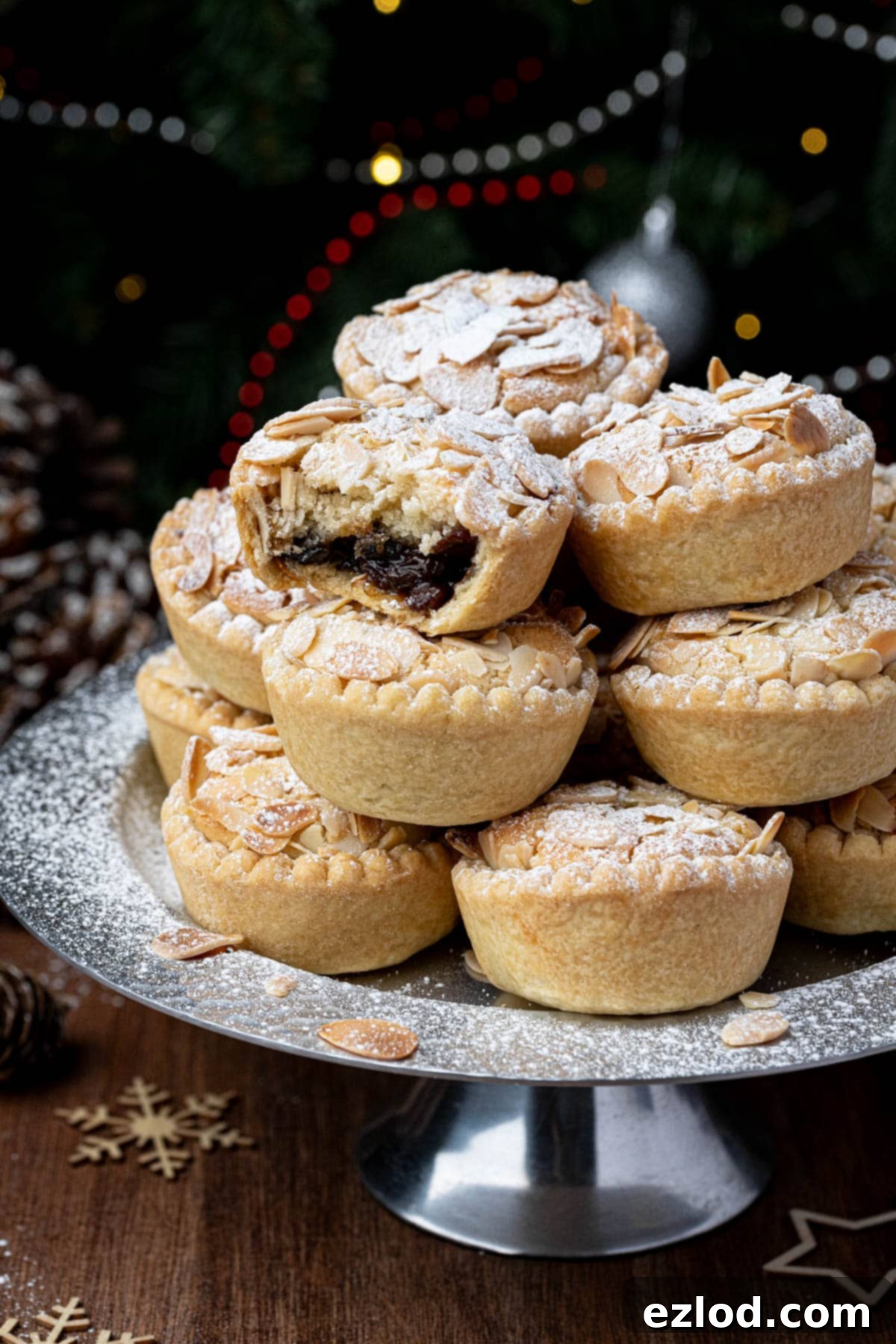 Close up of a stack of vegan frangipane mince pies on a metal cake stand, one with a bite taken out of it.