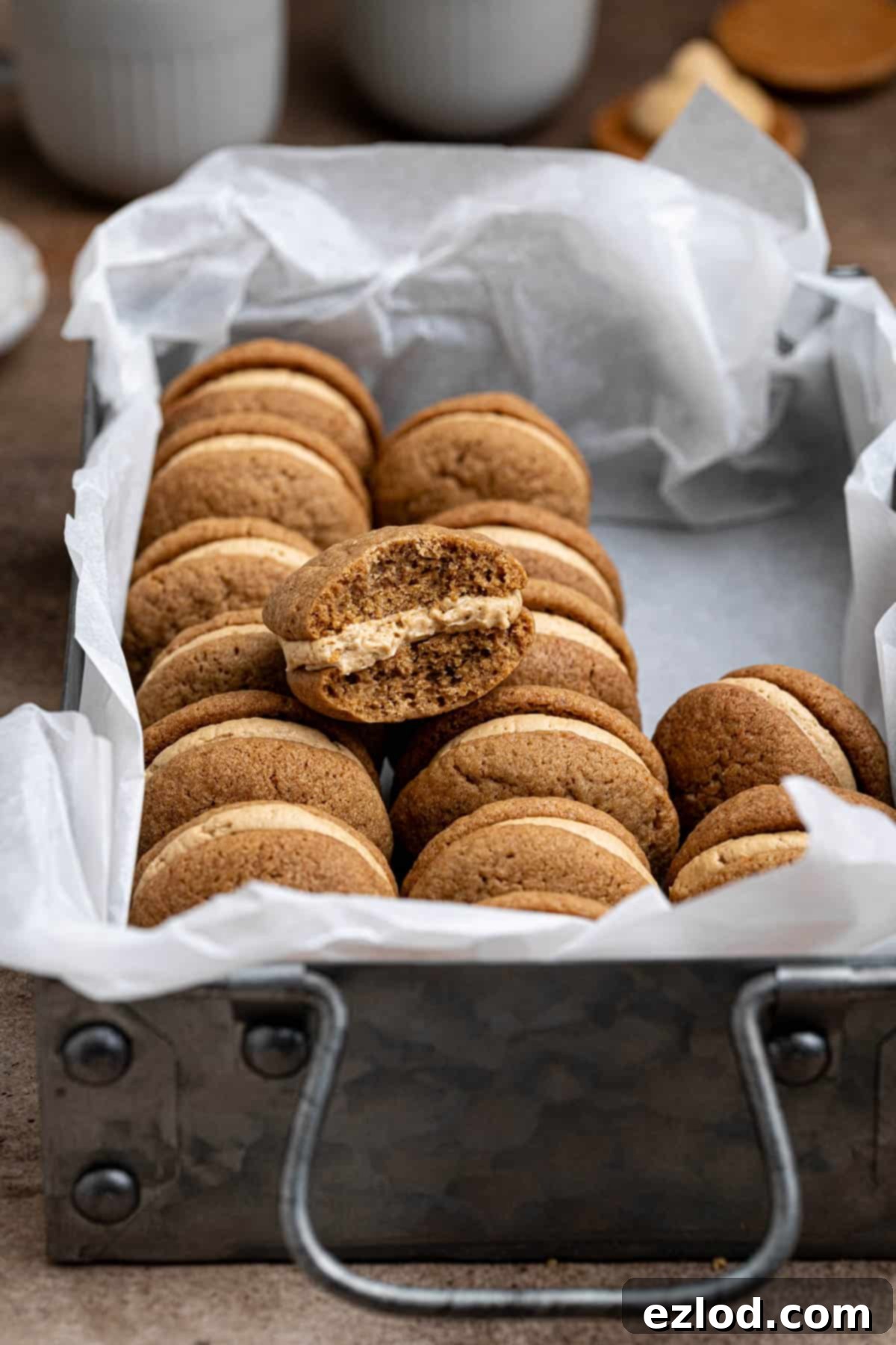 A mouth-watering view of vegan coffee kisses arranged in a metal tray, with one perfectly showcasing a bite already taken.
