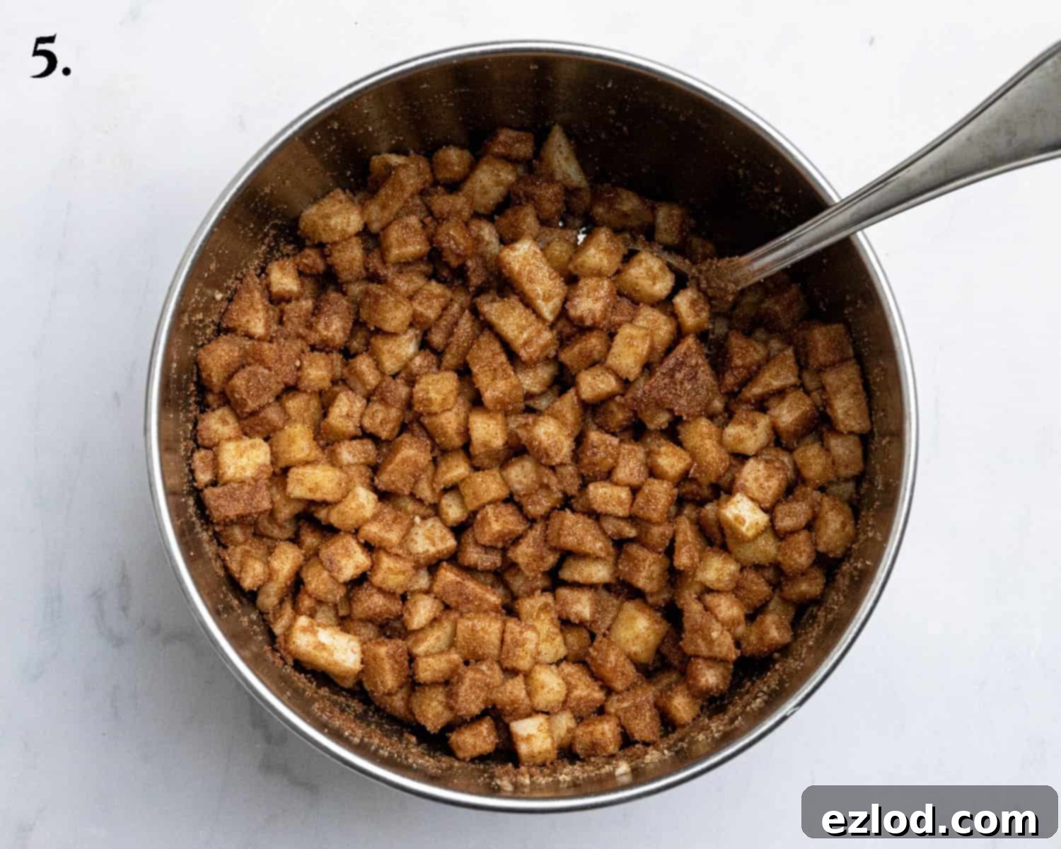 Step 5: The freshly prepared apple filling, mixed with brown sugar, cinnamon, and cornflour, resting in a bowl.