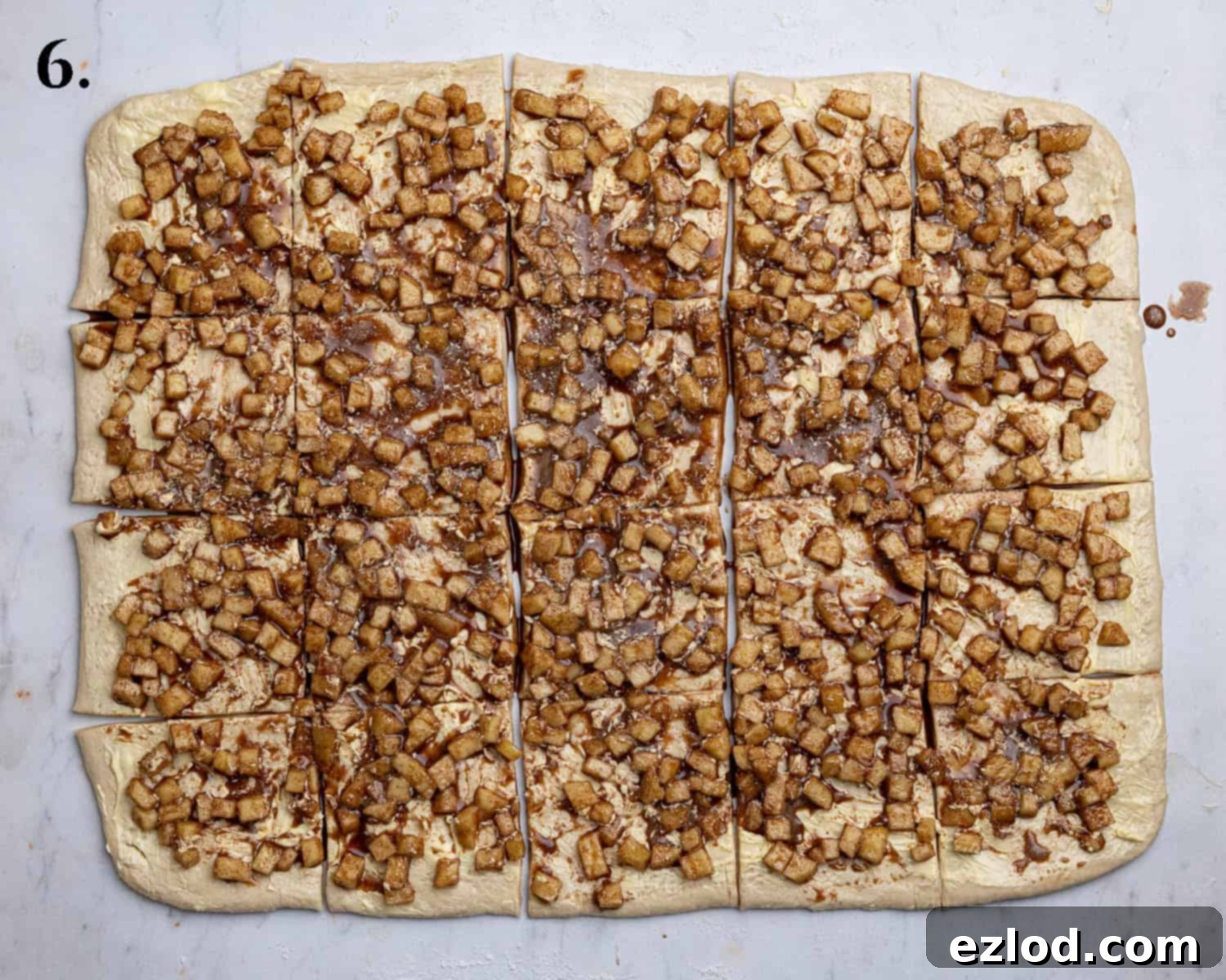 Step 6: The dough rectangle with apple filling spread evenly and cut into 20 squares using a pizza cutter, ready for stacking.
