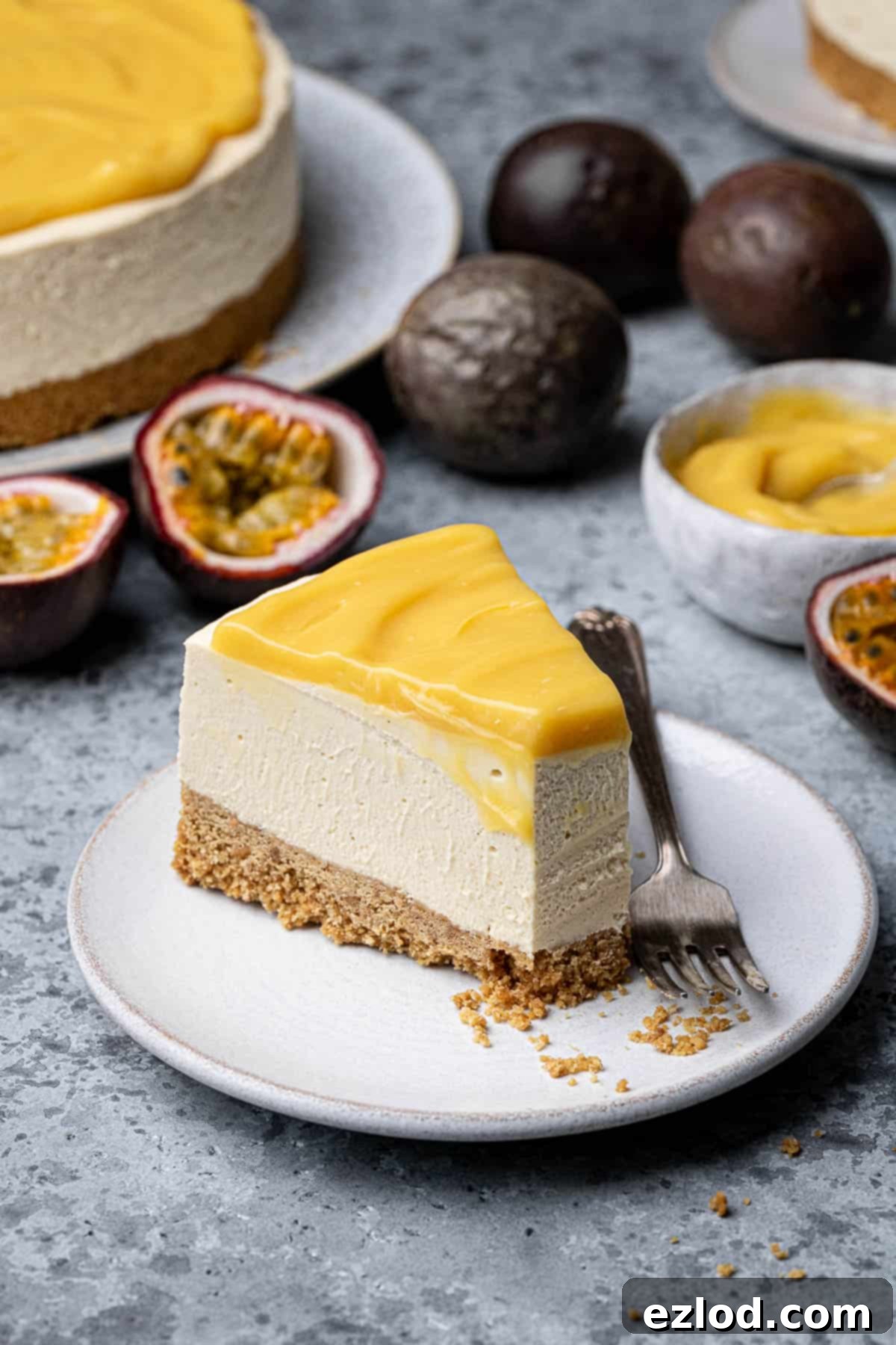 A beautifully presented slice of vegan passion fruit cheesecake on a white plate with a fork taking a bite.