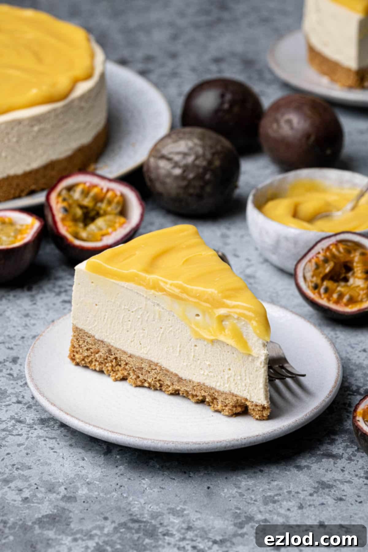 A vibrant slice of vegan passion fruit cheesecake, with whole and halved passion fruits artistically arranged in the background.