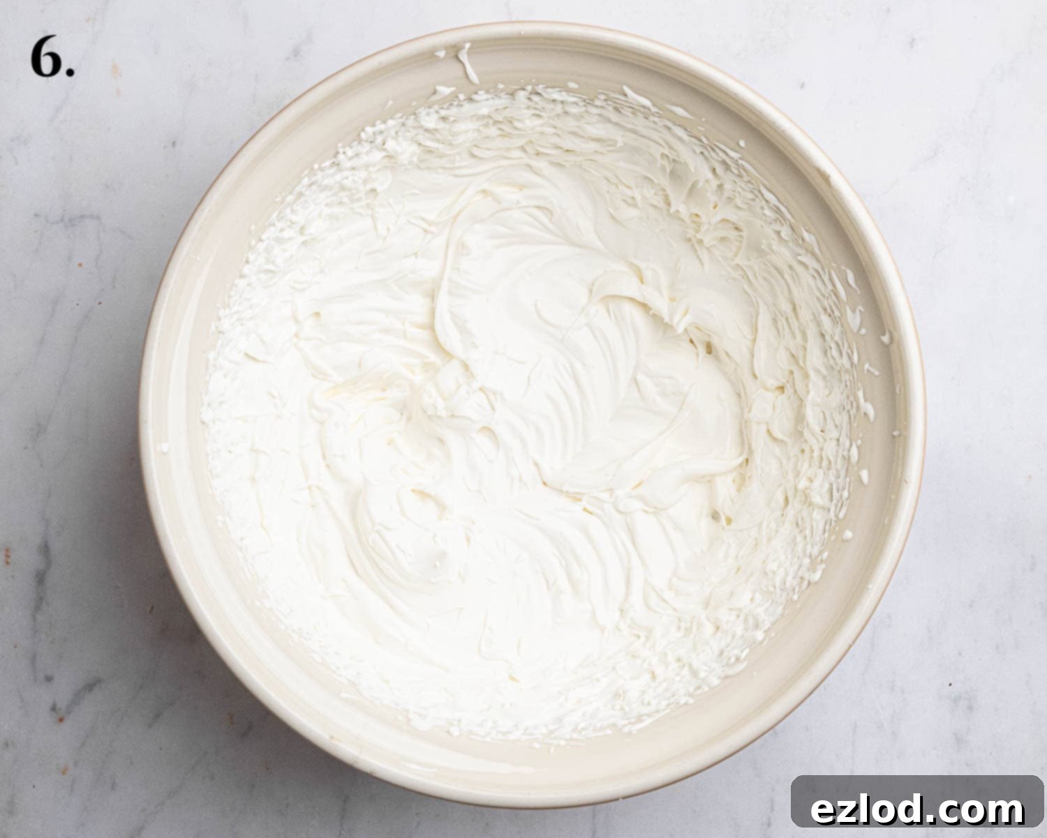 Step 6: Vegan whipping cream and icing sugar whipped to stiff peaks in a bowl, ready for folding.