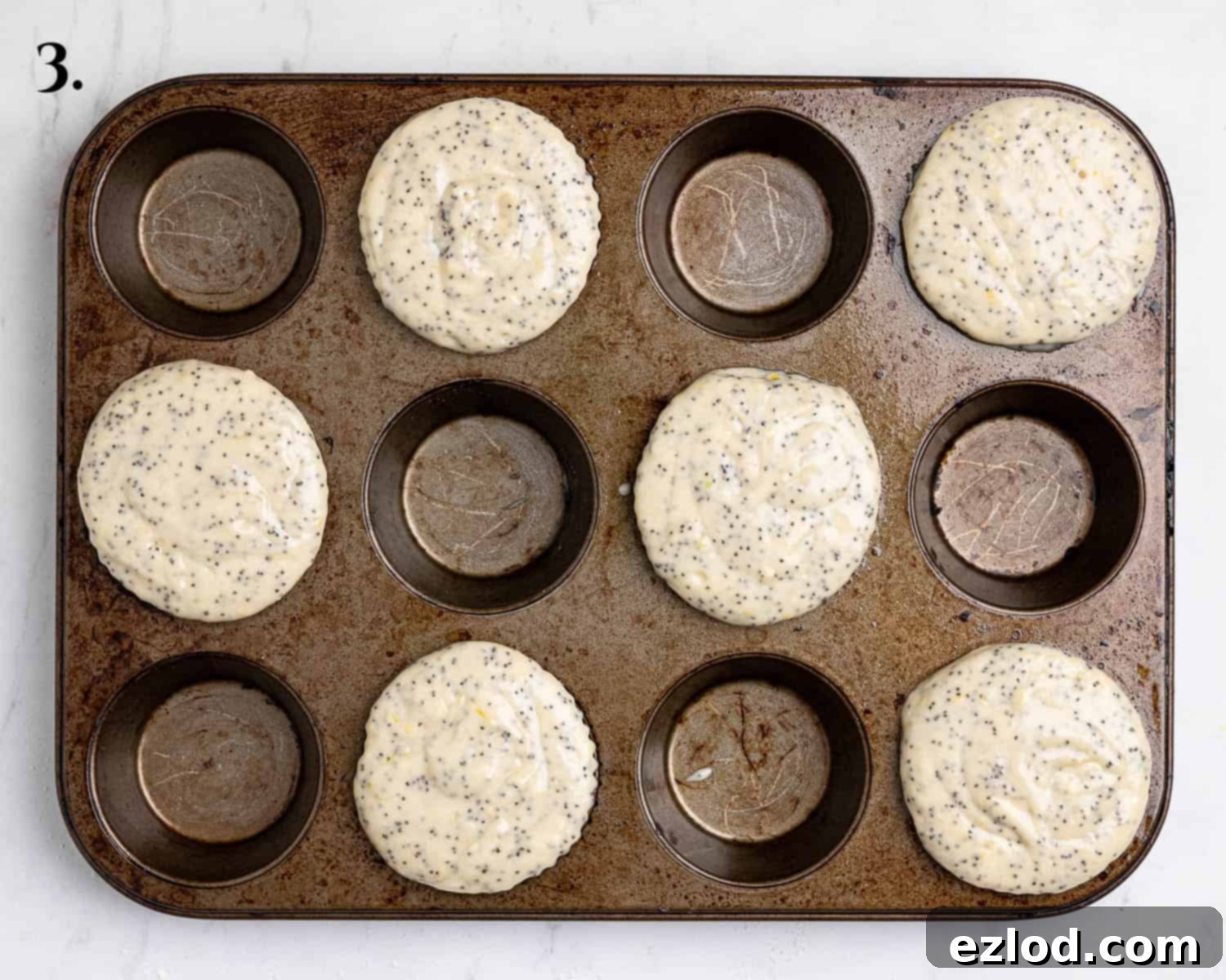 Step 3: Muffin batter carefully divided between muffin cases, filling each one right to the brim, ready for baking.