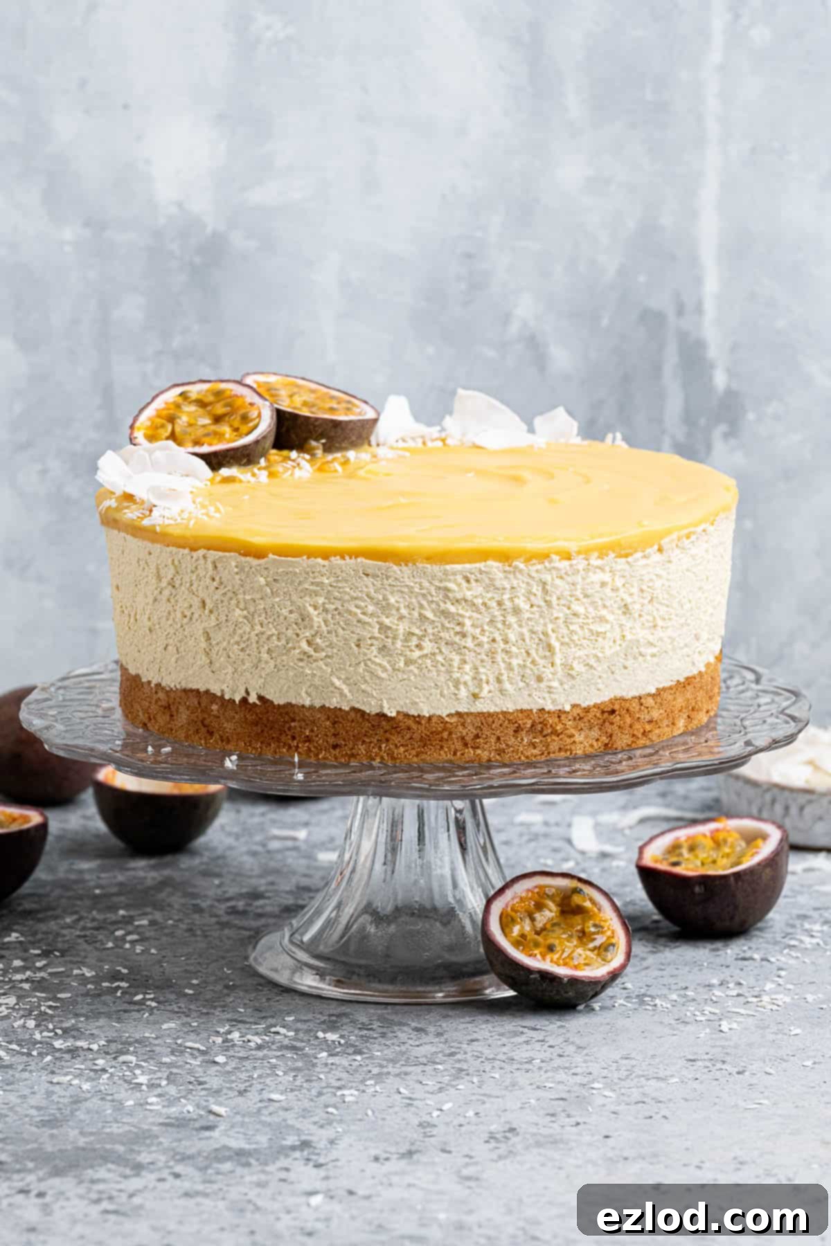 Vegan passion fruit mousse cake on a glass cake stand with fresh passion fruits.