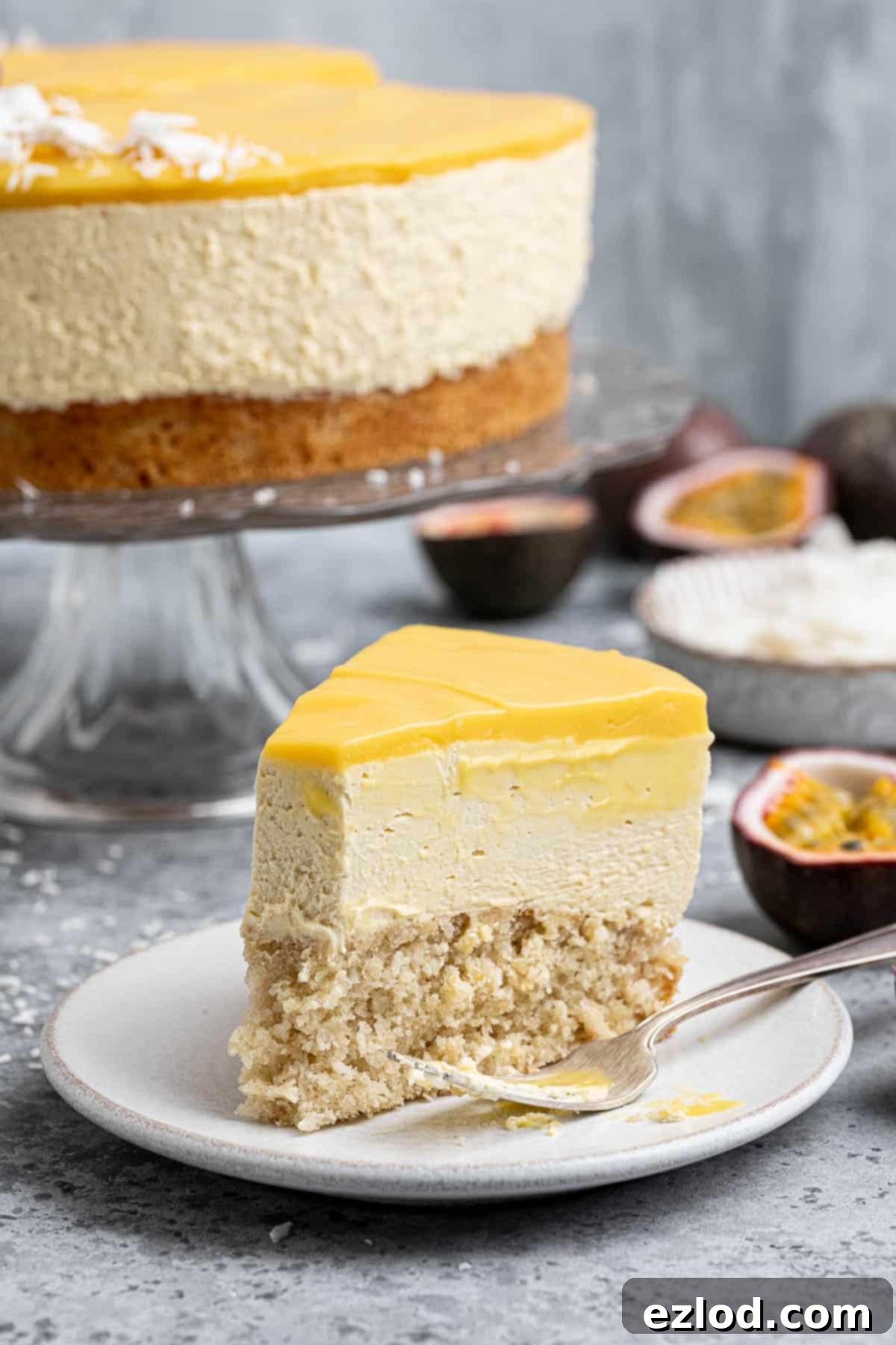 A slice of vegan passion fruit mousse cake on a plate with a forkful removed.