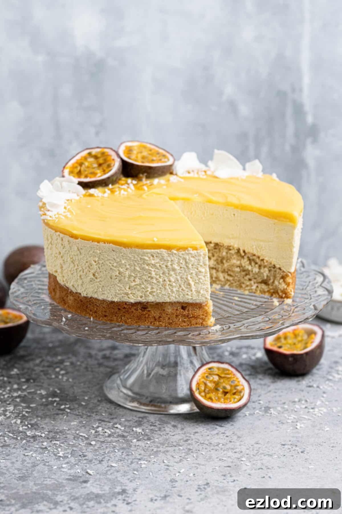 Vegan passion fruit mousse cake on a glass cake stand with a slice removed.