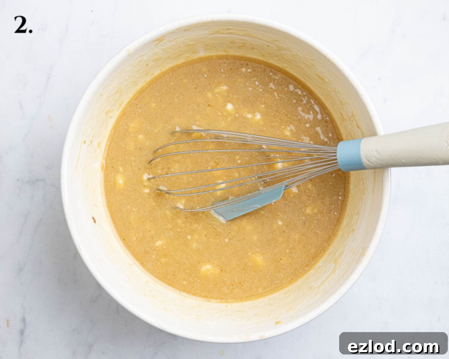 Step 2: A mixing bowl containing the wet ingredients – mashed banana, oil, yogurt, sugar, vinegar, and vanilla extract – whisked together until smooth.