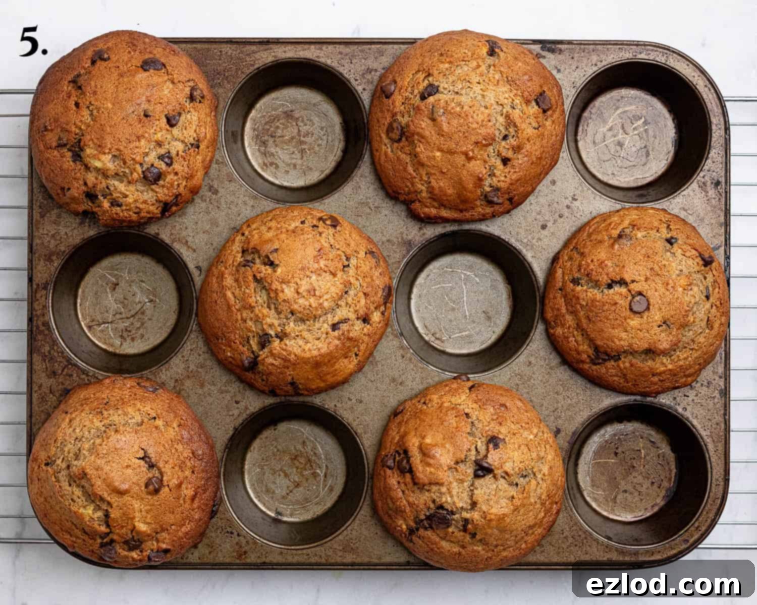 Step 5: Freshly baked vegan banana muffins cooling slightly in the muffin tin, showing their golden-brown, domed tops.