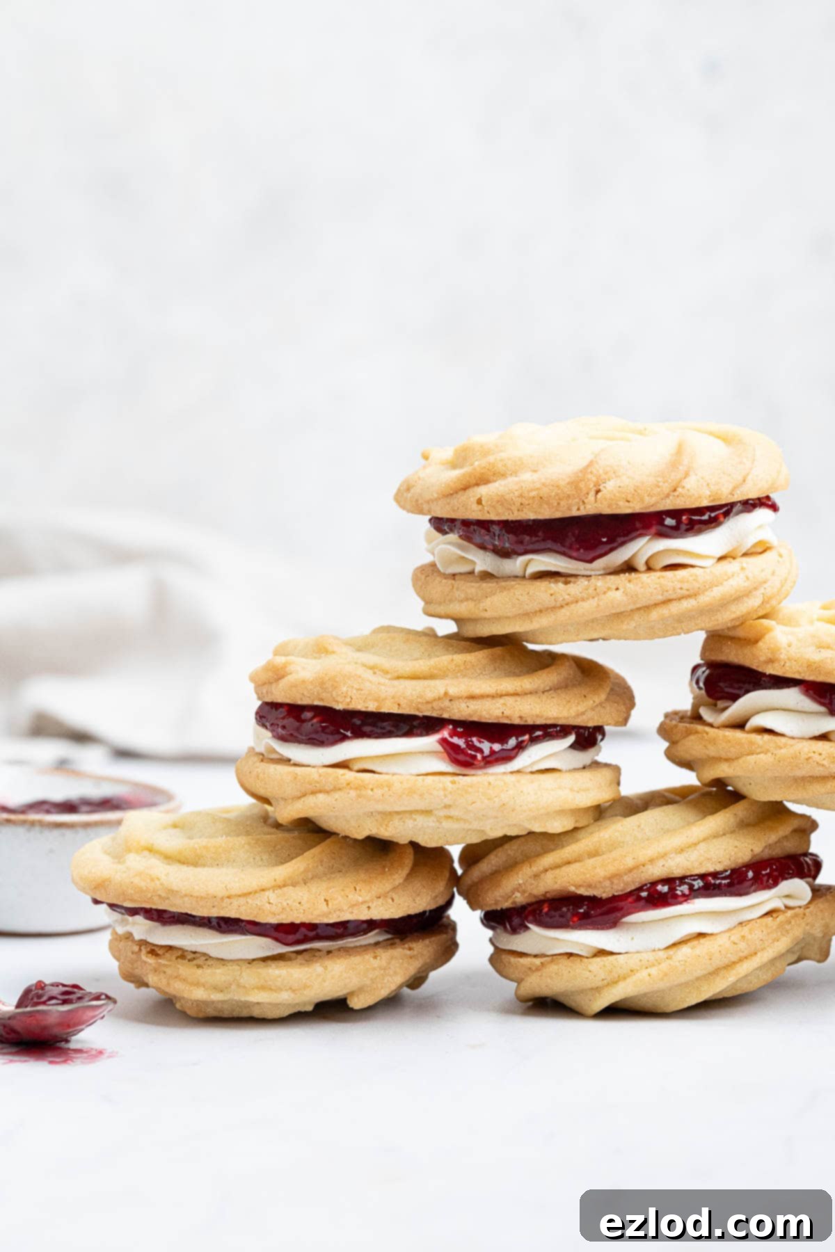 Dairy-Free Viennese Delights 12 A beautifully presented stack of vegan Viennese whirls, with a small bowl and spoon of jam nearby, inviting indulgence.