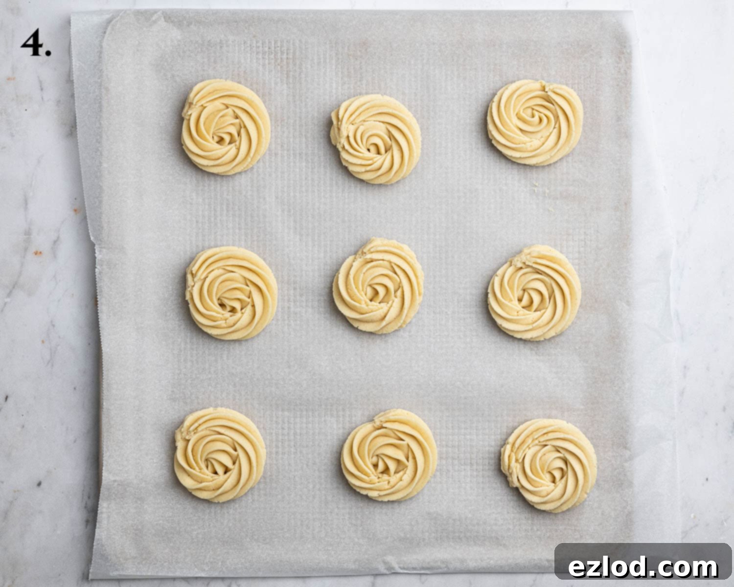 Dairy-Free Viennese Delights 8 Step 4 in making vegan Viennese whirls: Perfectly piped dough swirls arranged on a baking sheet, ready for the oven.