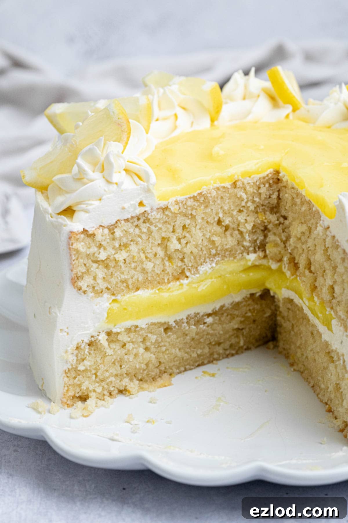 A close-up view of a perfectly sliced vegan lemon layer cake, revealing its beautiful layers of moist cake, fluffy buttercream, and vibrant lemon curd.