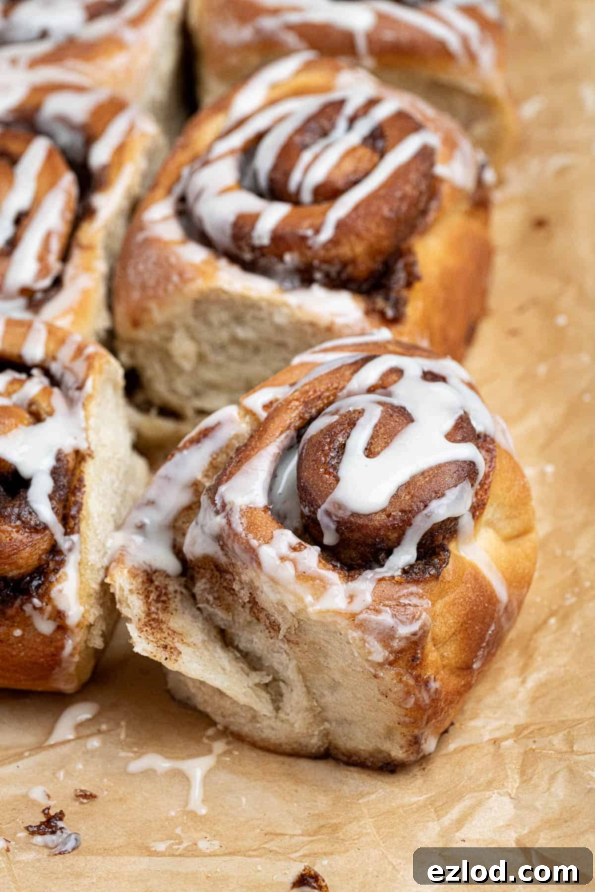 A partially unravelled olive oil cinnamon roll on a sheet of baking paper.