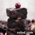 A stack of vegan black forest brownies with a cherry on top.