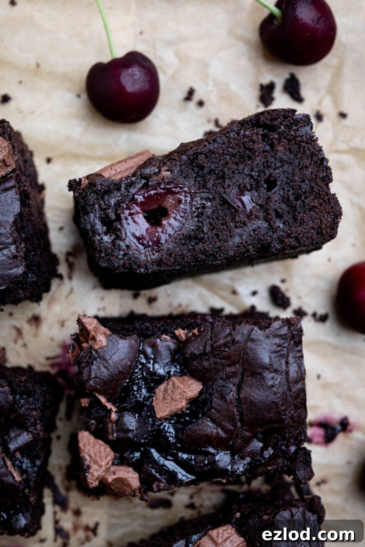 Close up of a moist and rich vegan cherry brownie, showing the cherries and fudgy texture.