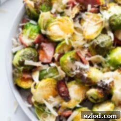 A plate of air fried Brussels sprouts topped with hot honey, bacon, and parmesan cheese.