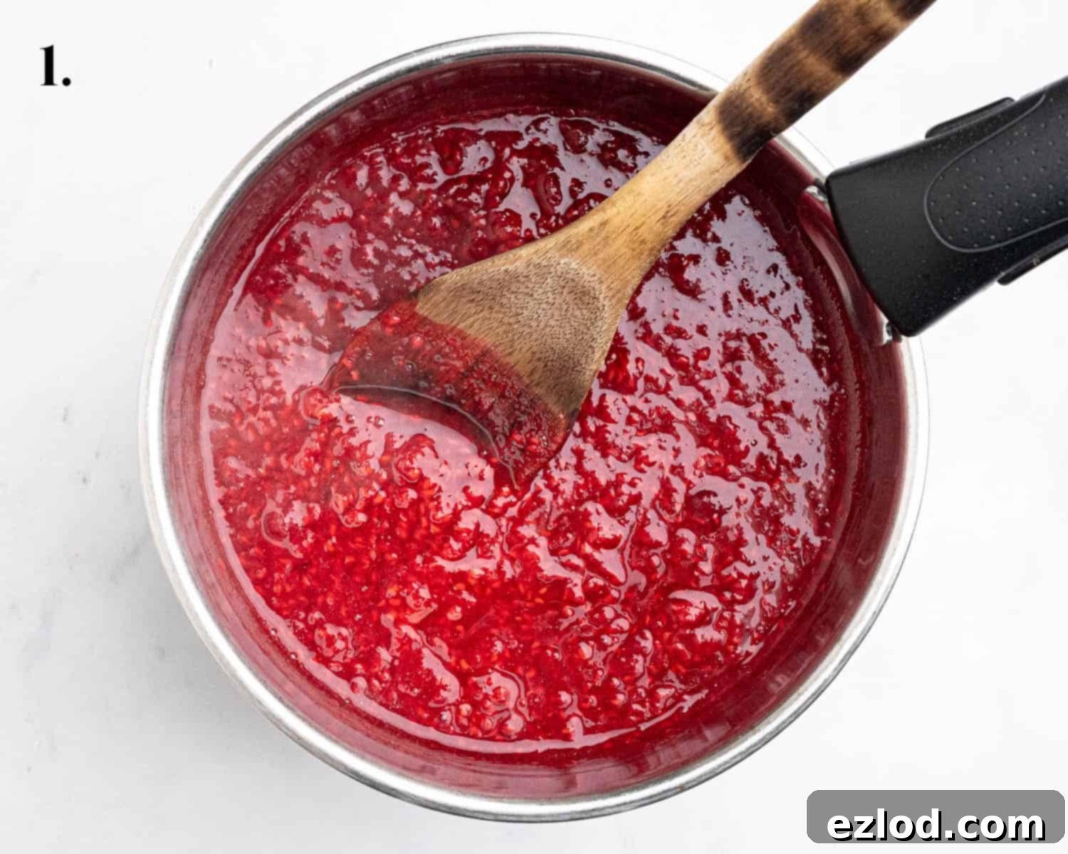 Step 1 in making vegan raspberry curd: A saucepan containing cooked, softened raspberries and lemon juice, ready for the next stage.