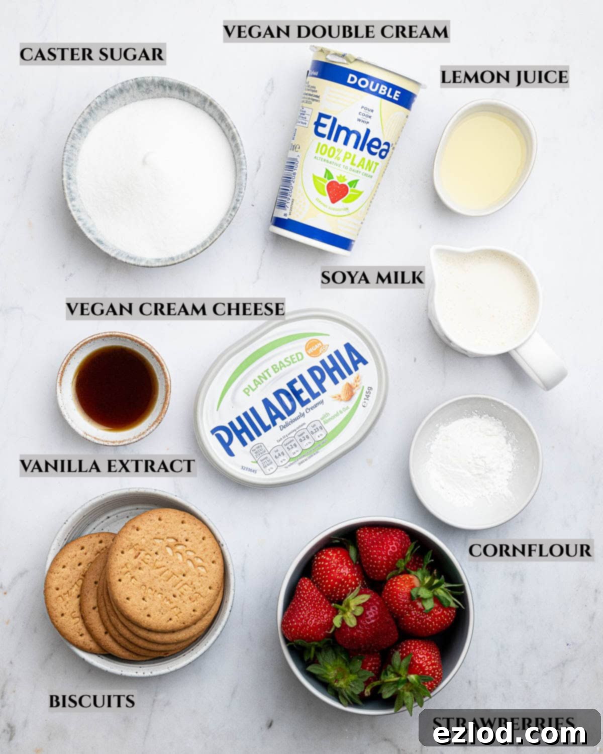 A flat lay photograph showing all the essential ingredients laid out for making vegan strawberry cheesecake ice cream, clearly labelled.
