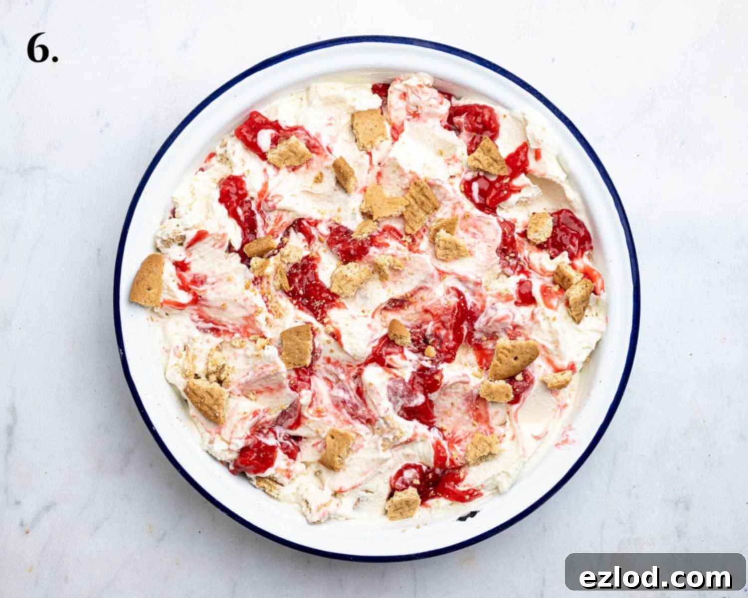 Step 6 in making vegan strawberry cheesecake ice cream: the churned ice cream layered with strawberry sauce and gently swirled in a freezer container.