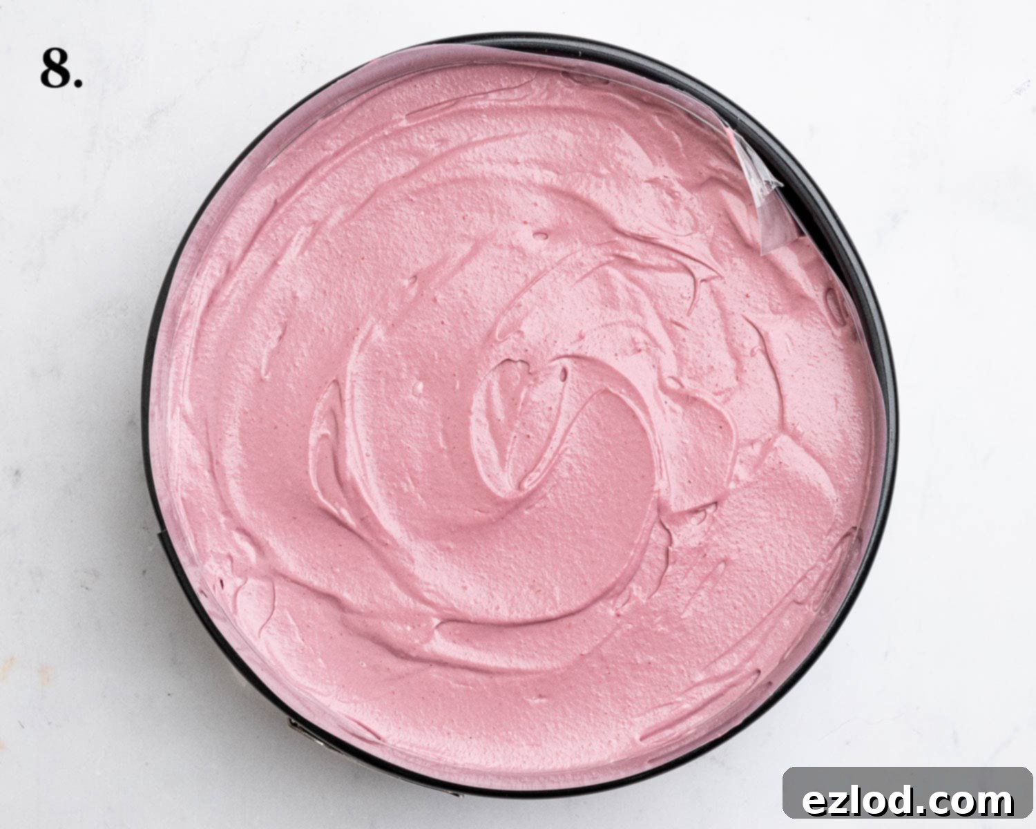 Step 8, the assembled vegan raspberry cheesecake in its tin, with the smooth filling poured over the biscuit base.