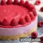 Vegan raspberry cheesecake topped with fresh raspberries on a metal plate.