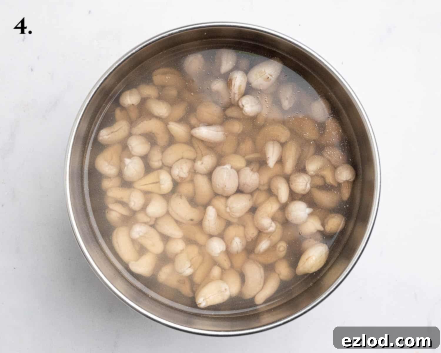 Step 4, unroasted cashews soaking in boiling water in a bowl, preparing them for blending.