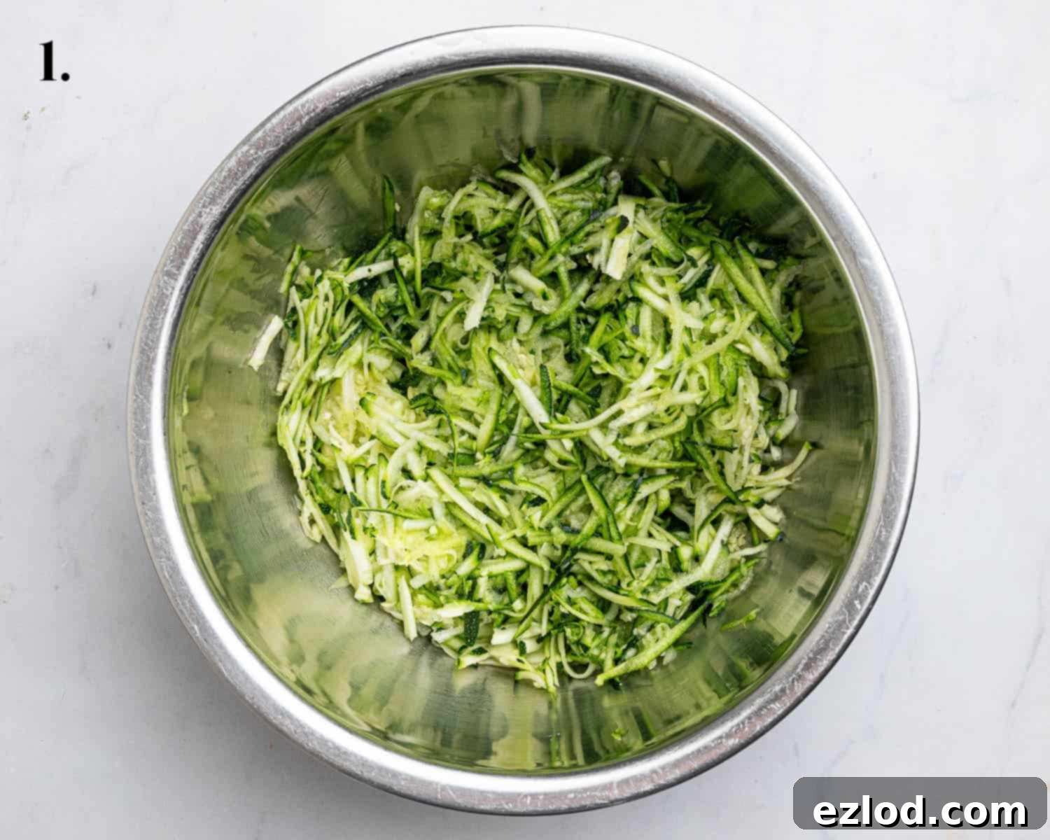 Vegan Zucchini Spice Cake 5 Step 1: Freshly coarsely grated courgette, carefully weighed and placed in a large mixing bowl, ready for mixing.