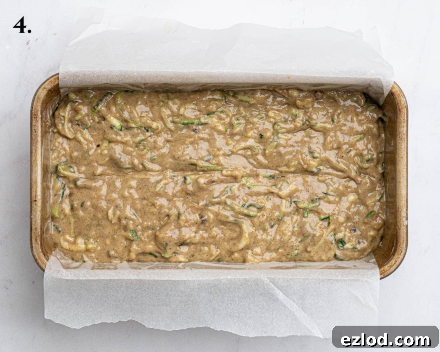 Vegan Zucchini Spice Cake 8 Step 4: The prepared spiced courgette cake batter poured into a parchment-lined loaf tin, leveled and ready to be placed into the preheated oven for baking.