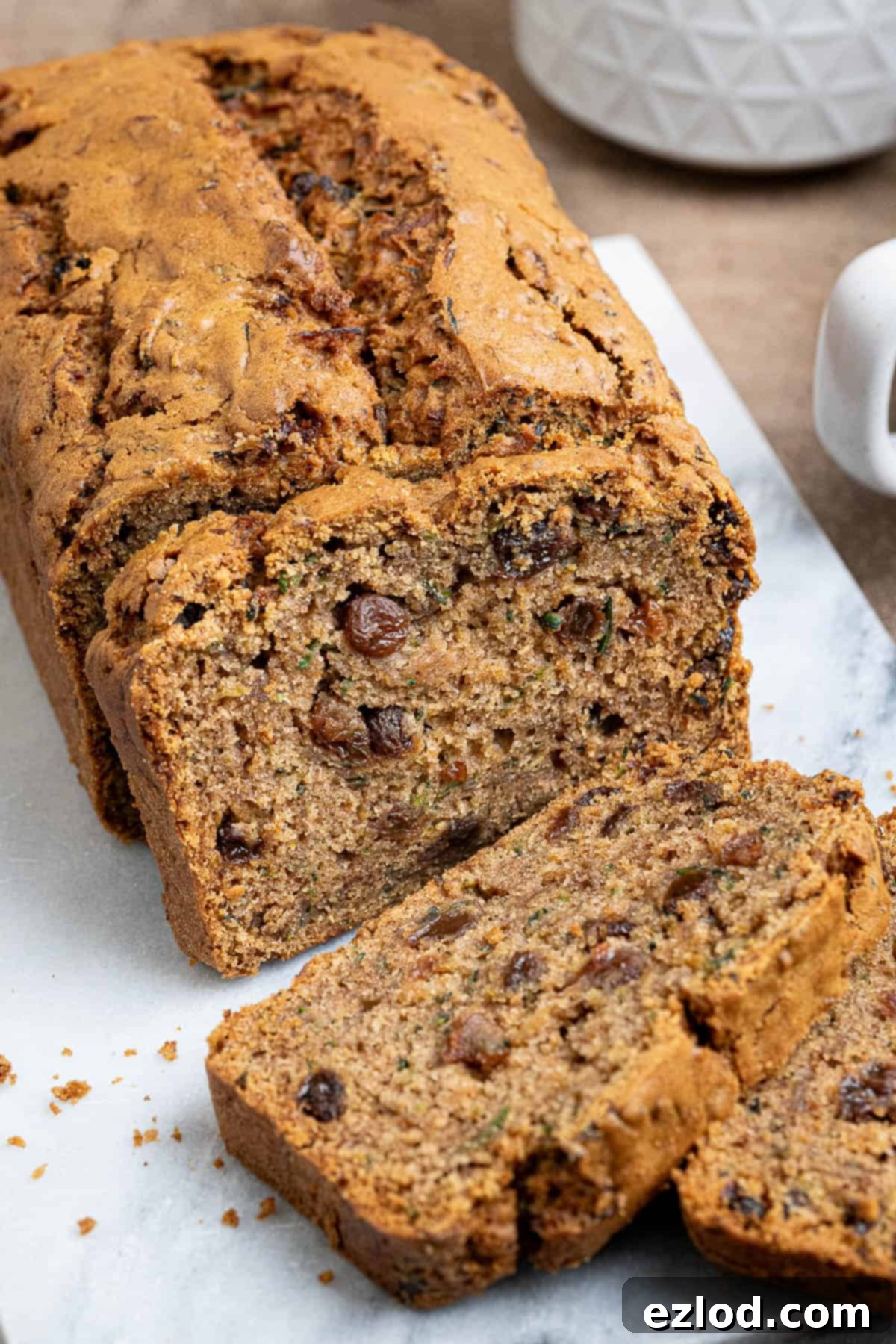 Vegan Zucchini Spice Cake 9 A close-up shot of a perfectly baked and sliced vegan spiced courgette cake, revealing its moist crumb and scattered sultanas, ready to be enjoyed.