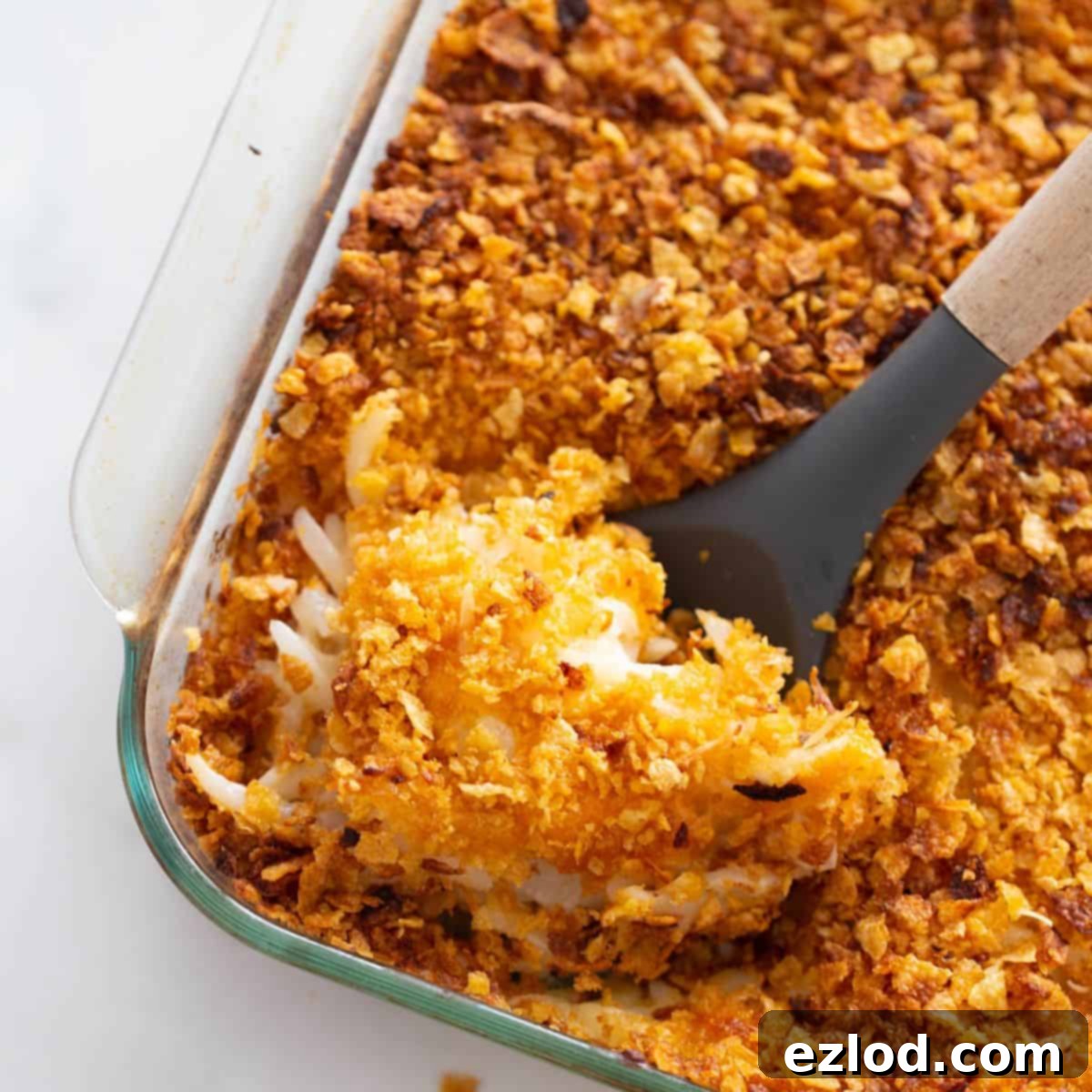 Healthy Cheesy Gluten-Free Hashbrown Delight 2 A pan of lightened up funeral potatoes with a serving spoon.