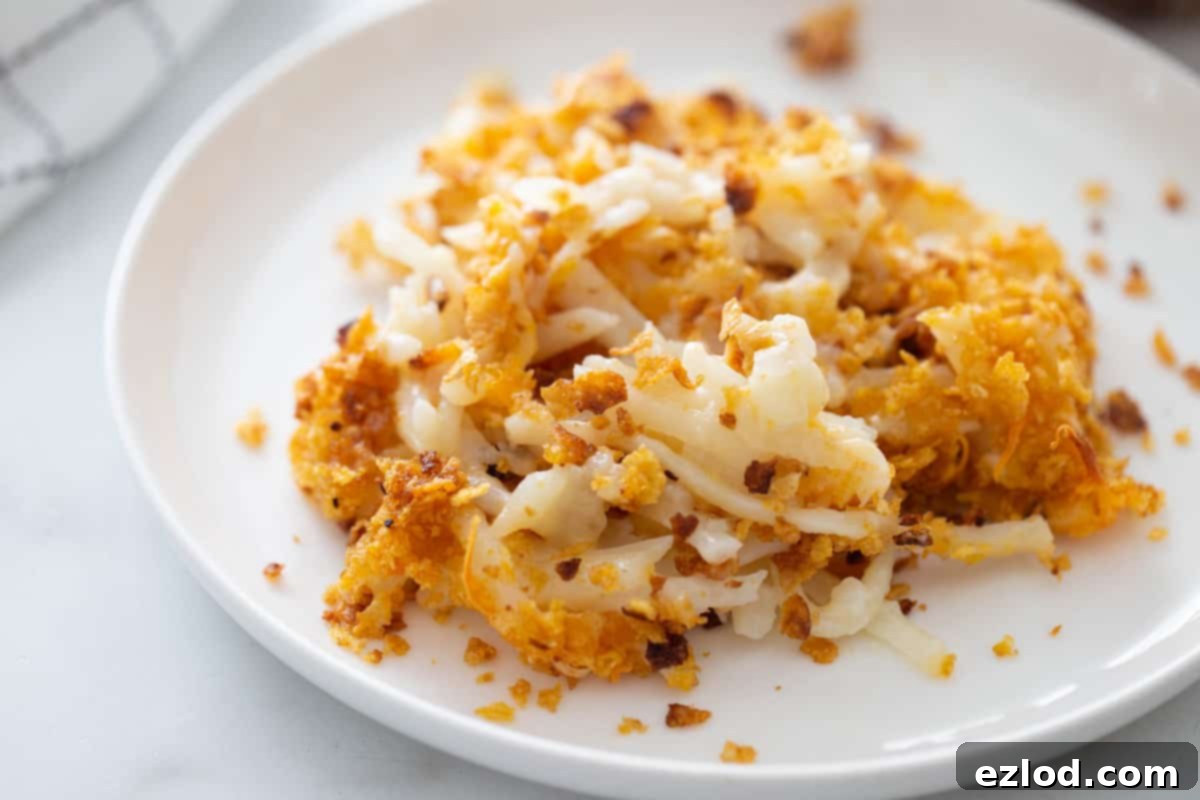 Healthy Cheesy Gluten-Free Hashbrown Delight 3 A white plate with cheesy hash brown casserole topped with cornflakes.