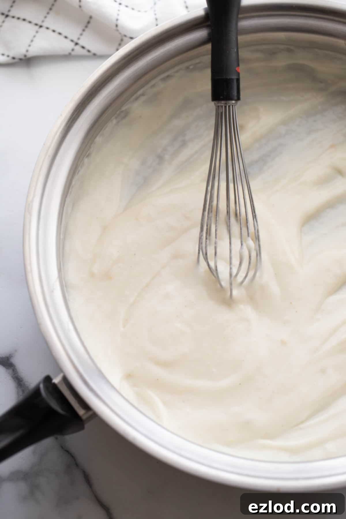 A saucepan with homemade cream of chicken soup and a wire whisk