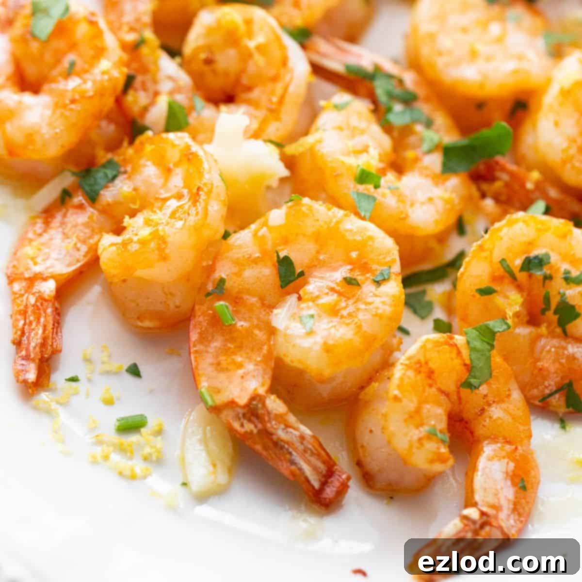 Close up of Air Fryer Shrimp on a white platter with fresh herbs.