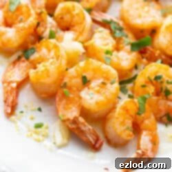 Close up of Air Fryer Shrimp on a white platter with fresh herbs.