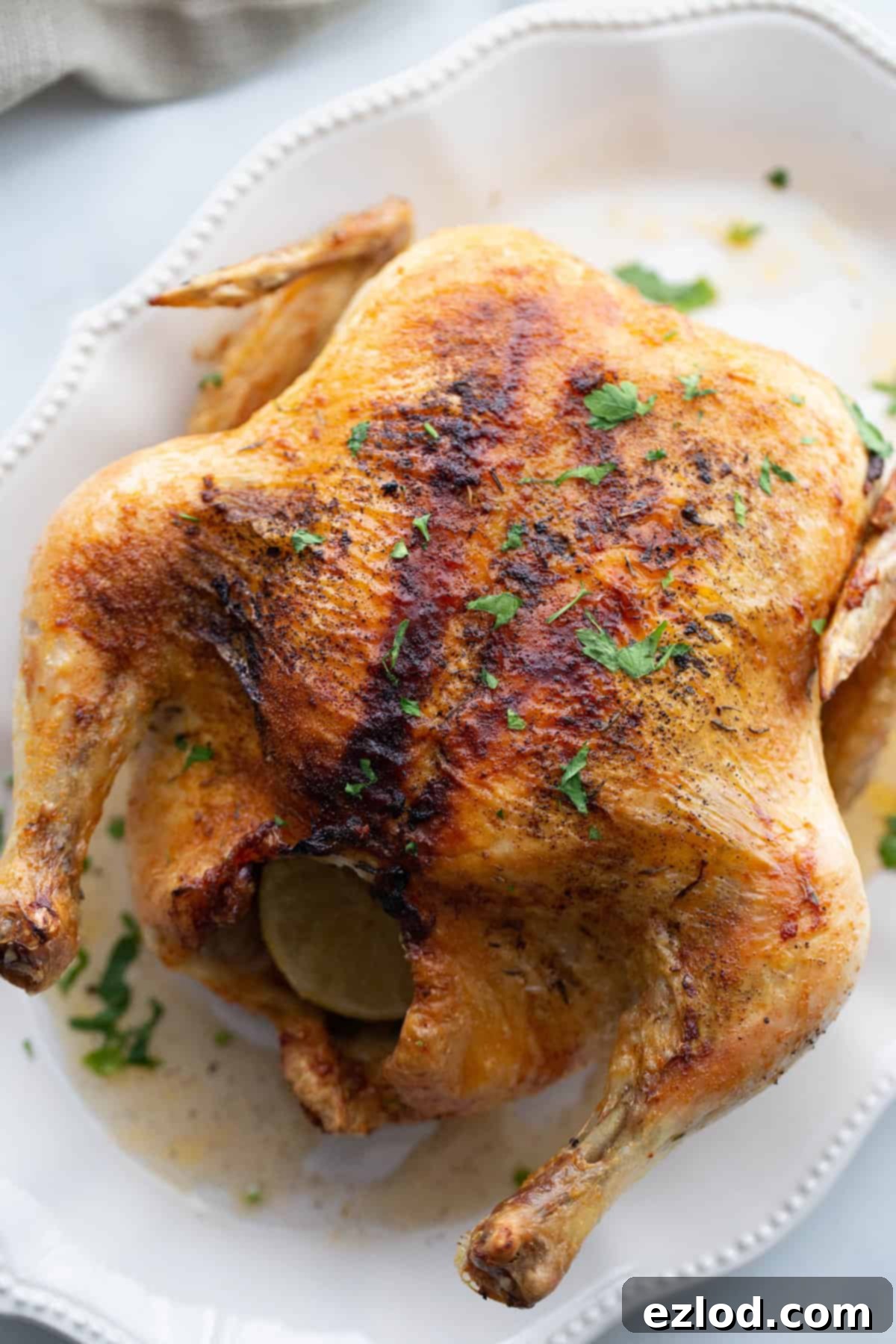 A golden-brown air fryer whole chicken presented on a white platter, ready for carving and serving.