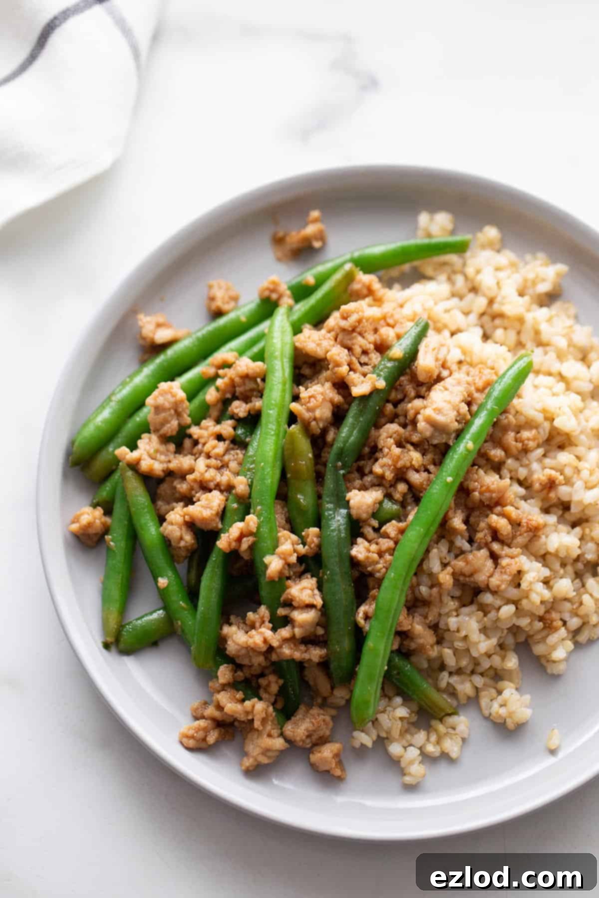 A white background and white plate with a quick ground chicken stir fry dish.