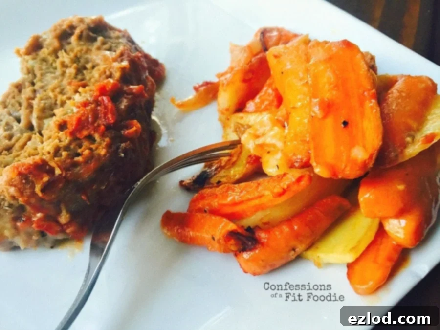 A white plate with a piece of Momma's meatloaf with tomato sauce and sliced carrots and potatoes on the side, highlighting a complete, comforting meal.