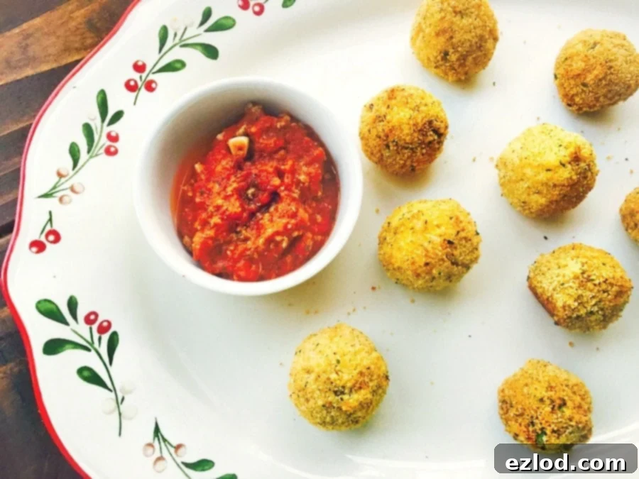 A festive platter holding golden brown Mini Arancini Rice Balls, served with a side of rich marinara sauce, perfect for holiday gatherings.
