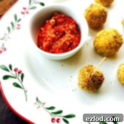 Mini Arancini Rice Balls on a white, red, and green Christmas Platter with Marinara Sauce for dipping on the side.