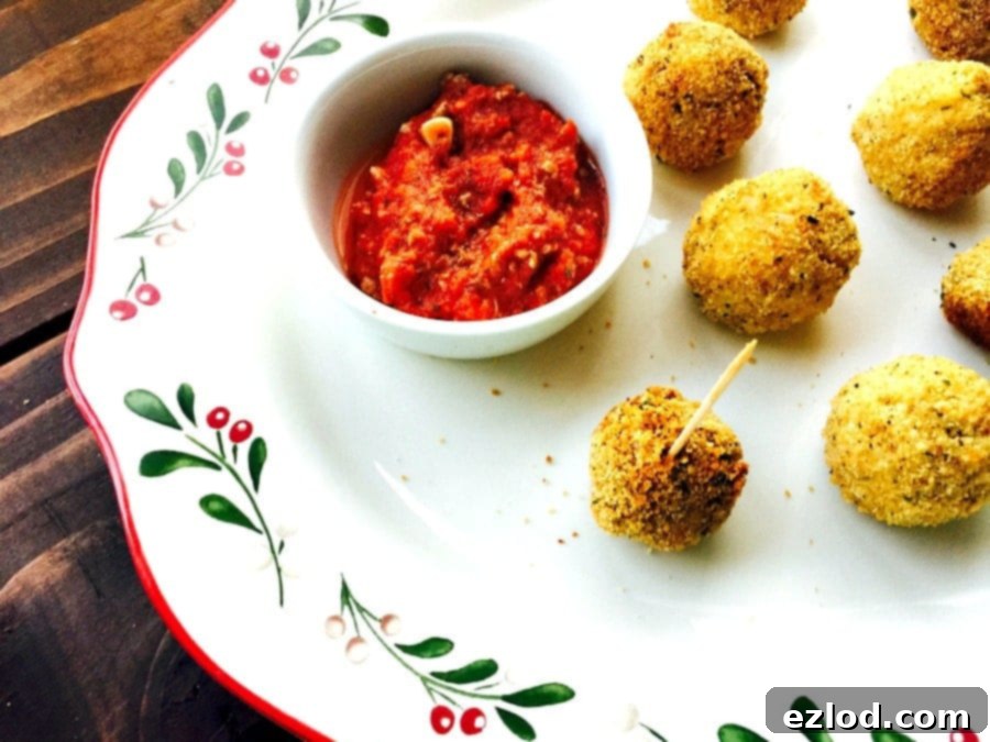 A closer look at a selection of golden, crispy Mini Arancini Rice Balls presented on a festive holiday platter with marinara dipping sauce.