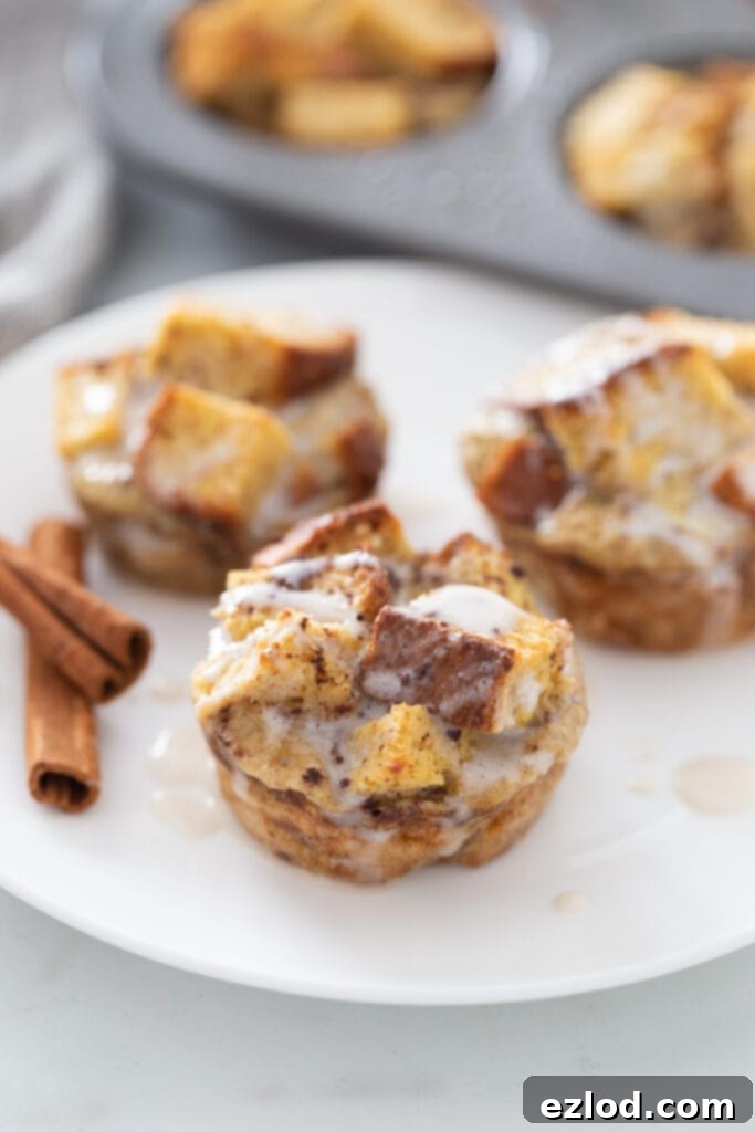 Three French toast cups are on a white plate, garnished with a sprinkle of cinnamon.