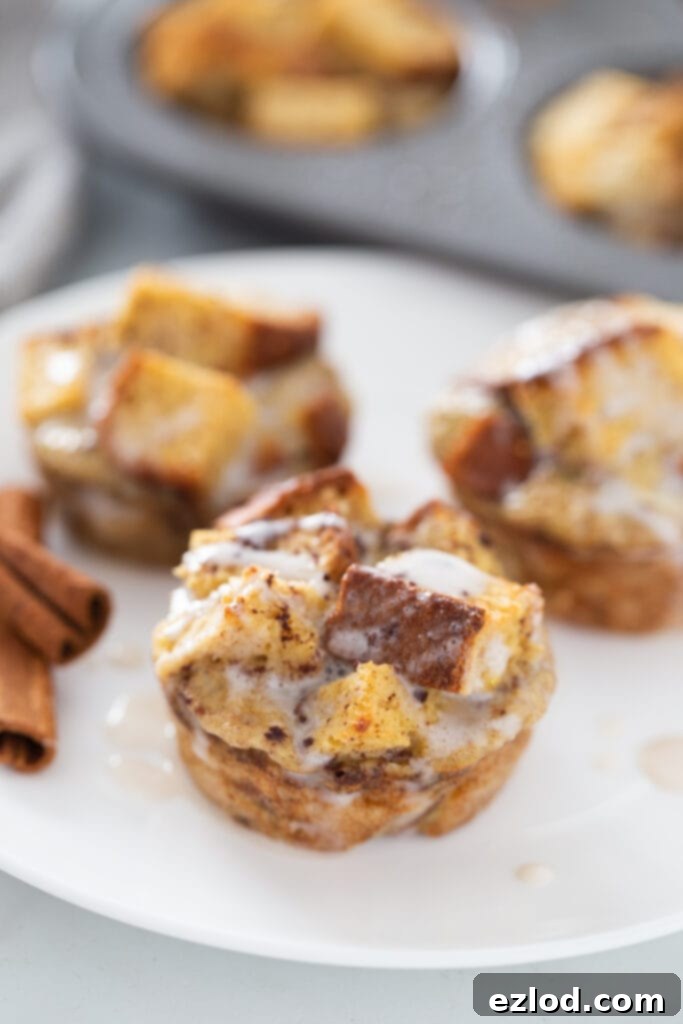 Cinnamon sticks are artistically arranged on a white plate alongside two healthy cinnamon roll French toast casserole cups, hinting at the warm spice flavor.