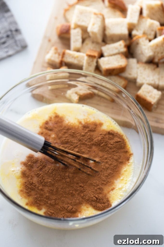 The ingredients for healthy French toast casserole cups are neatly laid out on a clean white surface, including bread, eggs, cinnamon, and almond milk.